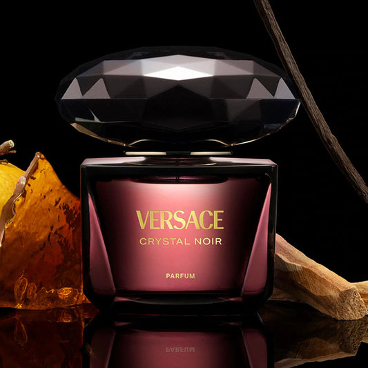 Versace Crystal Noir perfume bottle with decorative elements on a reflective surface